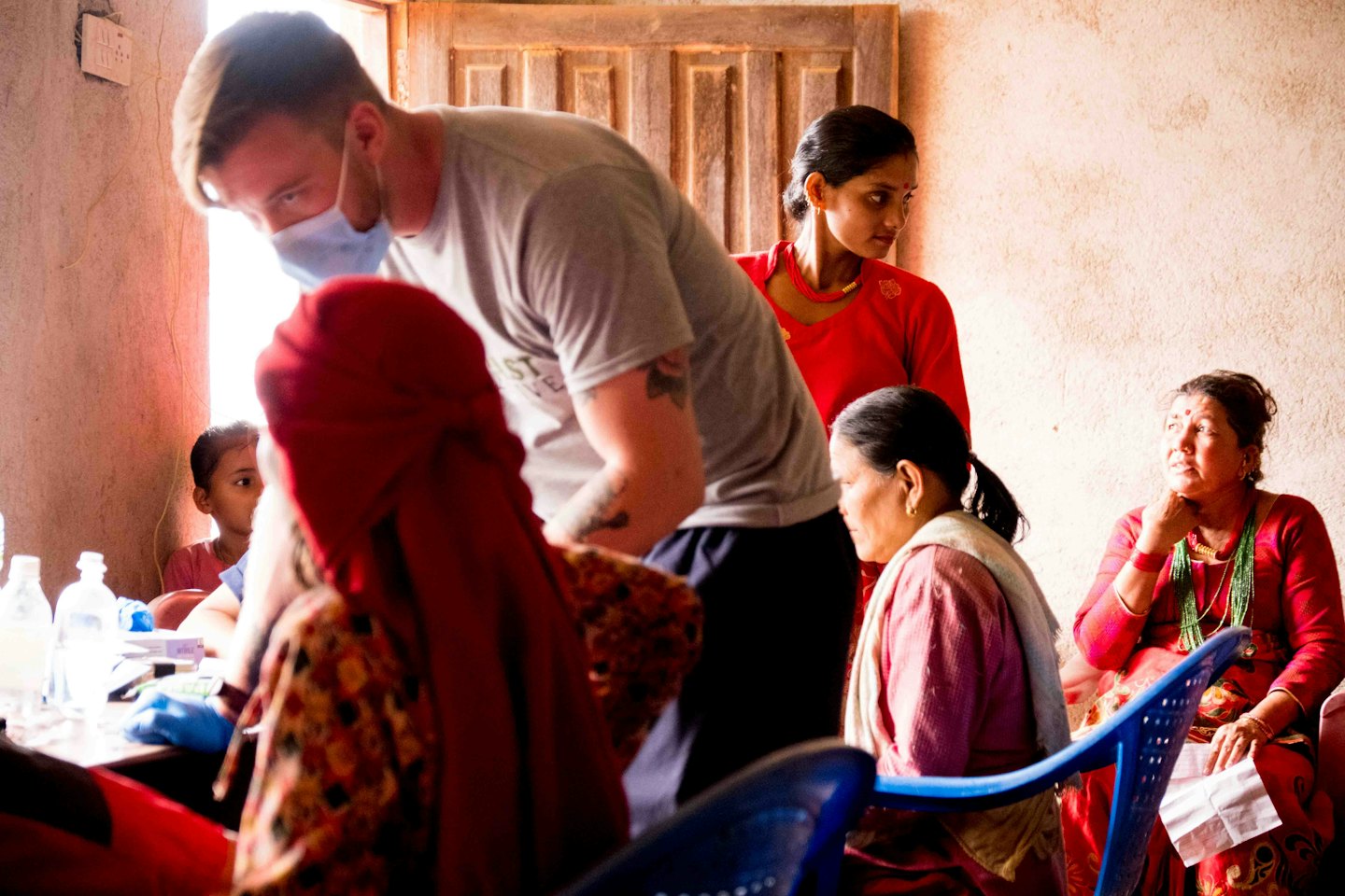 A medical professional consults with women and a child indoors.